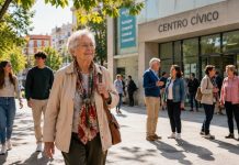 Envejecer con derechos: la deuda democrática con los mayores Persona mayor caminando con autonomía por una plaza luminosa junto a personas de distintas generaciones, con un centro cívico al fondo.