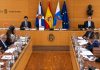 Cabildo de Tenerife: acuerdos y deudas del pleno de junio Sesión plenaria del Cabildo de Tenerife en su salón institucional, con representantes en las mesas de debate, presidencia, banderas oficiales y documentación de trabajo.