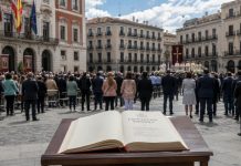 Laicidad pendiente: cuando se confunde respeto con pleitesía Constitución Española abierta en primer plano ante una ceremonia cívico-religiosa en una plaza institucional, como símbolo del debate sobre la laicidad pendiente y la neutralidad del Estado.