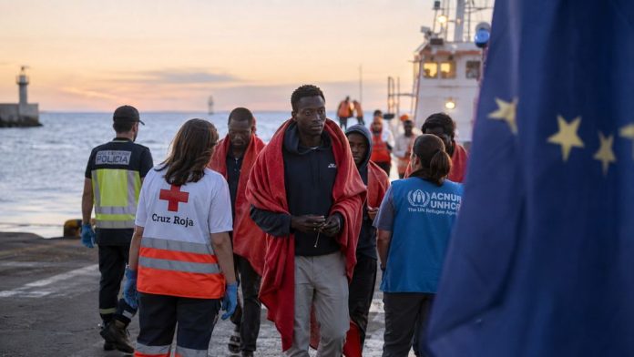 Personas migrantes son atendidas en un muelle canario al amanecer por personal humanitario y servicios públicos, con una bandera europea desenfocada al fondo que simboliza la responsabilidad compartida de Europa ante la migración.