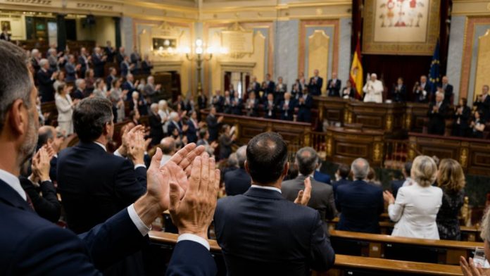Hemiciclo del Congreso durante una ovación solemne, con representantes públicos de pie aplaudiendo a un pontífice situado en la tribuna, en una escena que simboliza la distancia entre el gesto institucional y la coherencia política posterior.