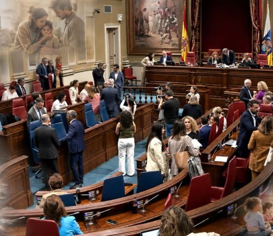 Pleno canario de junio: datos frente a la vida real Salón de plenos del Parlamento de Canarias con alusiones difuminadas a la vivienda, la sanidad, la infancia, la migración y la educación.