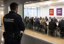 Sindicatos de clase y Policía Nacional: derechos con uniforme Policía nacional observa desde un pasillo acristalado una reunión sindical, simbolizando el debate sobre su acceso a los sindicatos de clase.