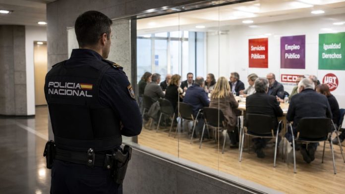 Policía 1 Policía nacional observa desde un pasillo acristalado una reunión sindical, simbolizando el debate sobre su acceso a los sindicatos de clase.