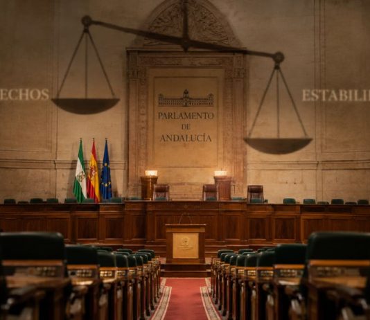 Pacto PP Vox Andalucía: derechos en retirada Interior vacío del Parlamento de Andalucía, con una gran balanza proyectada sobre el hemiciclo y las palabras “Derechos” y “Estabilidad” a ambos lados.