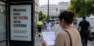 CEOE y bajas laborales: una campaña contra el enfermo Mujer con un parte de incapacidad temporal frente a una marquesina sobre el absentismo laboral, con un hospital y varios trabajadores al fondo.