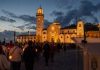 Día de Tenerife: el 2 de febrero ya tenía nombre Procesión de las candelas en la plaza de la Basílica de Candelaria al anochecer, con un atril institucional desenfocado en primer plano.