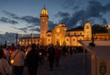 Día de Tenerife: el 2 de febrero ya tenía nombre Procesión de las candelas en la plaza de la Basílica de Candelaria al anochecer, con un atril institucional desenfocado en primer plano.