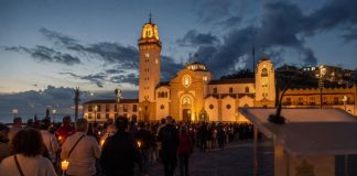 Día de Tenerife: el 2 de febrero ya tenía nombre Procesión de las candelas en la plaza de la Basílica de Candelaria al anochecer, con un atril institucional desenfocado en primer plano.