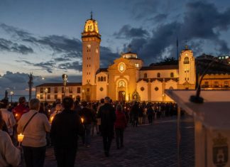 Día de Tenerife: el 2 de febrero ya tenía nombre Procesión de las candelas en la plaza de la Basílica de Candelaria al anochecer, con un atril institucional desenfocado en primer plano.