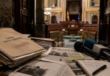 Condena de David Sánchez: justicia, política y lawfare Expedientes judiciales, recortes de prensa y micrófonos ante una sala institucional, como símbolo de la tensión entre justicia, medios y confrontación política.