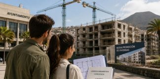 Licencias urbanísticas en Canarias: agilizar no basta Pareja observa una promoción de viviendas en construcción en Canarias mientras sostiene planos y una licencia urbanística, con un ayuntamiento y varias grúas al fondo.