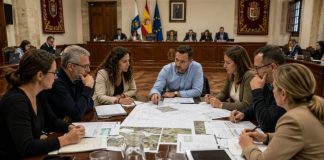 Oposición municipal: prepararse para gobernar Equipo plural de oposición analiza presupuestos, planos y proyectos municipales alrededor de una mesa situada frente al salón de plenos.