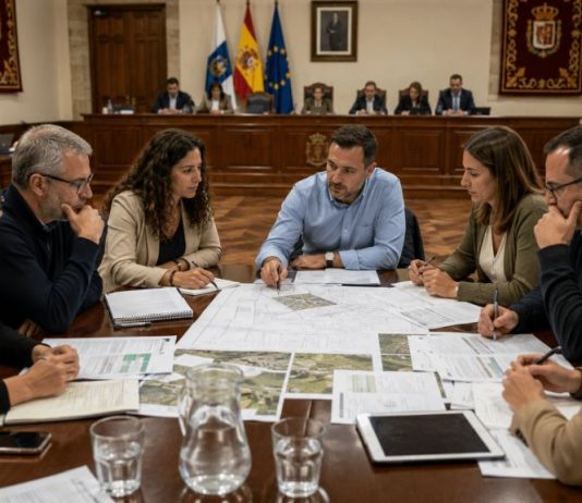 Oposición municipal: prepararse para gobernar Equipo plural de oposición analiza presupuestos, planos y proyectos municipales alrededor de una mesa situada frente al salón de plenos.