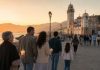 2 de febrero: firma para proteger la memoria de Candelaria Familias de varias generaciones caminan al atardecer hacia la Basílica de Candelaria, junto al mar, algunas con velas encendidas.