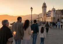 2 de febrero: firma para proteger la memoria de Candelaria Familias de varias generaciones caminan al atardecer hacia la Basílica de Candelaria, junto al mar, algunas con velas encendidas.