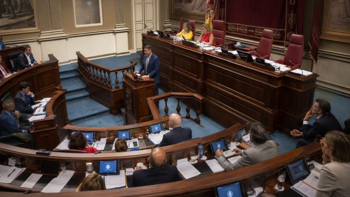Vista general del hemiciclo del Parlamento de Canarias durante el pleno de julio de 2026, con un diputado interviniendo desde la tribuna.
