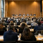 Ley de hierro: cómo el poder crea sus propias élites Asamblea democrática en un gran auditorio, con numerosos participantes frente a una pequeña mesa de dirigentes que concentra la atención y la toma de decisiones.