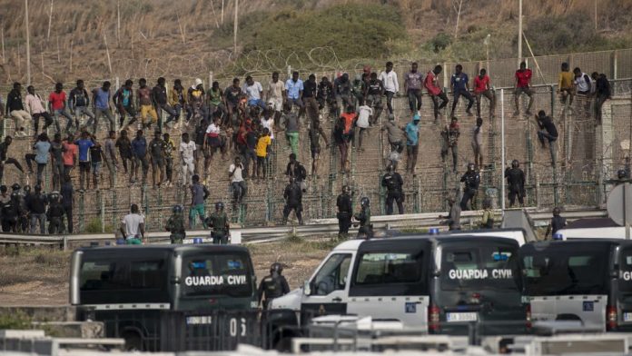 Invación 1 Migrantes junto a la valla fronteriza de Ceuta bajo vigilancia de la Guardia Civil durante una situación de fuerte presión migratoria.