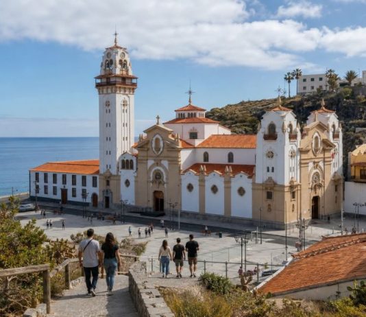 Afluencia en Candelaria: por qué hubo menos peregrinos Vista de la Basílica de Candelaria y su entorno costero con peregrinos descendiendo hacia la plaza y un aviso de restricción de sendero por riesgo de incendio.