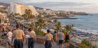 Prosperidad turística canaria: ¿quién gana realmente? Zona turística costera de Canarias con hoteles, playas, visitantes y trabajadores del sector, reflejo del contraste entre actividad turística y vida cotidiana.