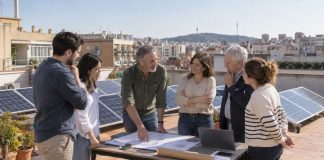 Autoconsumo colectivo: cómo compartir energía solar Reunión de vecinos en una azotea con placas fotovoltaicas para estudiar un proyecto de autoconsumo colectivo.