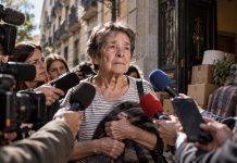 Culpa individual: la coartada para no hablar de vivienda Mujer mayor rodeada de cámaras y micrófonos frente a una vivienda, como símbolo de cómo un desahucio puede convertirse en juicio público sobre la persona.