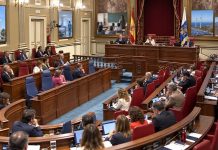 Pleno autonómico: siete debates para entender Canarias Salón de plenos del Parlamento de Canarias durante una sesión, con referencias visuales a vivienda, sanidad, educación, energía y territorio.