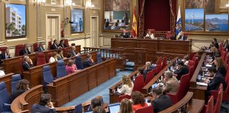 Pleno autonómico: siete debates para entender Canarias Salón de plenos del Parlamento de Canarias durante una sesión, con referencias visuales a vivienda, sanidad, educación, energía y territorio.