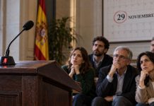 Pensiones y transparencia: Feijóo, Vox e Inda Cinco ciudadanos observan un atril vacío con el micrófono silenciado y un calendario que destaca el 29 de noviembre, como símbolo del silencio electoral.