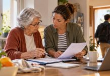Pensiones públicas: ¿quiebra real o alarmismo? Una mujer jubilada y otra de mediana edad revisan documentos económicos en la cocina de una vivienda, mientras un joven sale hacia el trabajo al fondo.